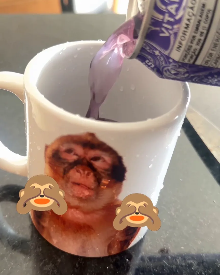 Caneca de cerâmica com estampa de meme do macaco sendo enchida com bebida